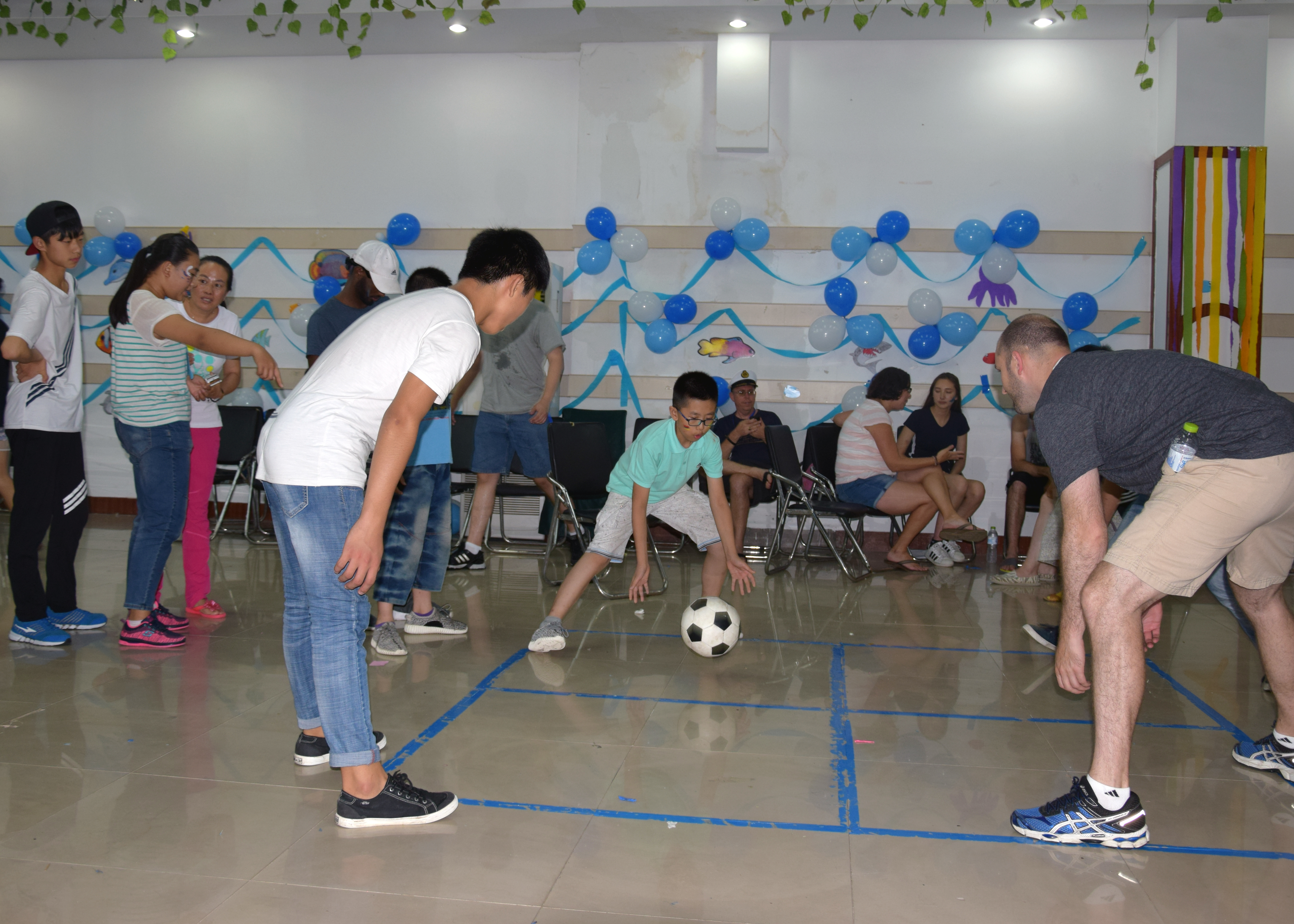 Children playing four square with teachers.