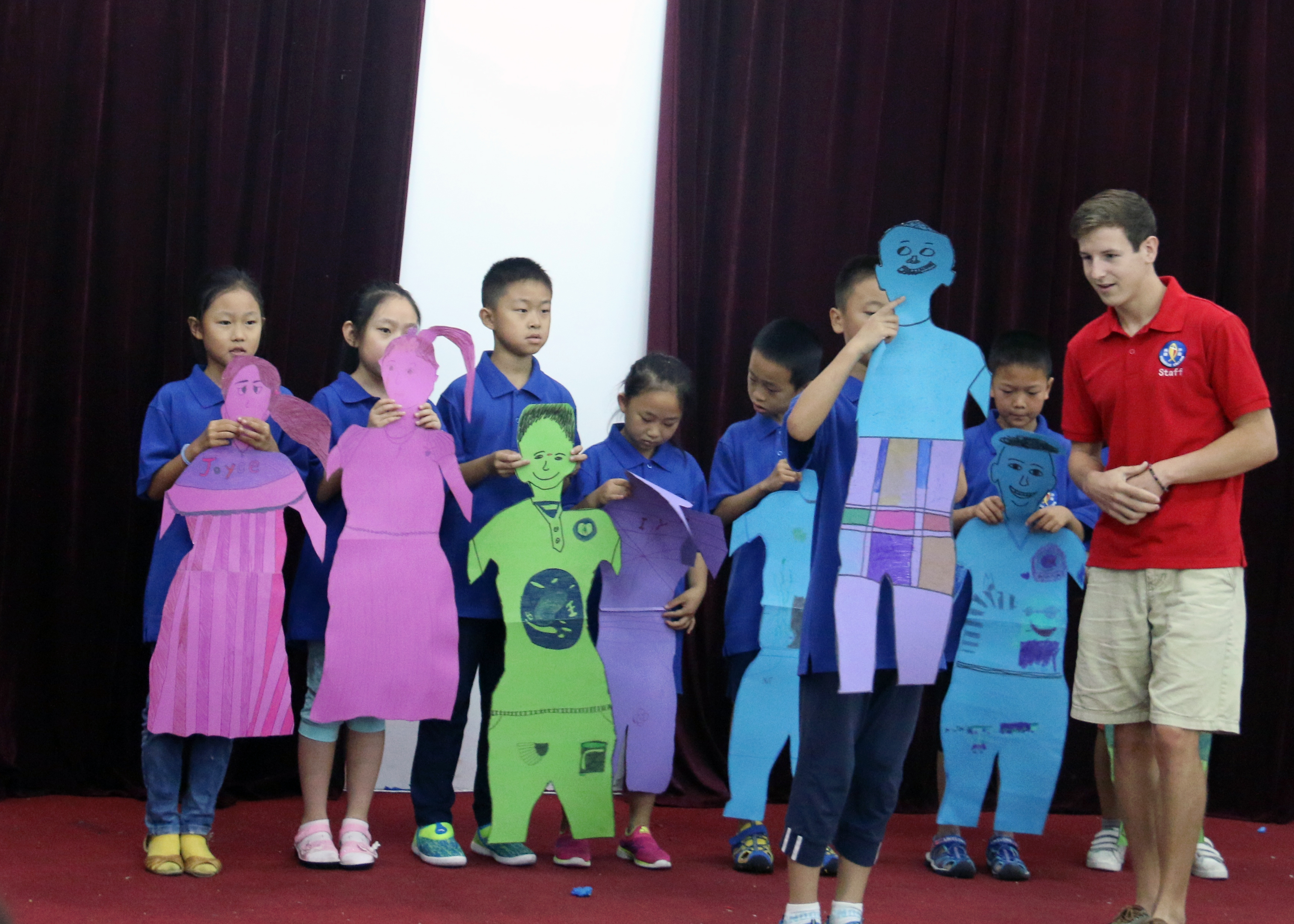 Children showing cut outs of themselves at camp.